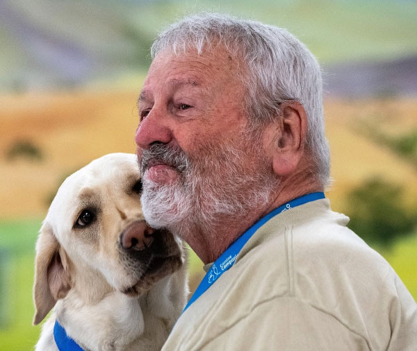 Photo shows the faces of an older man and a golden Labrador retriever