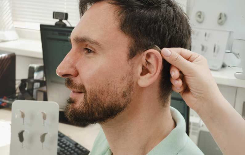 A man trying on hearing aids in an audiologist office.